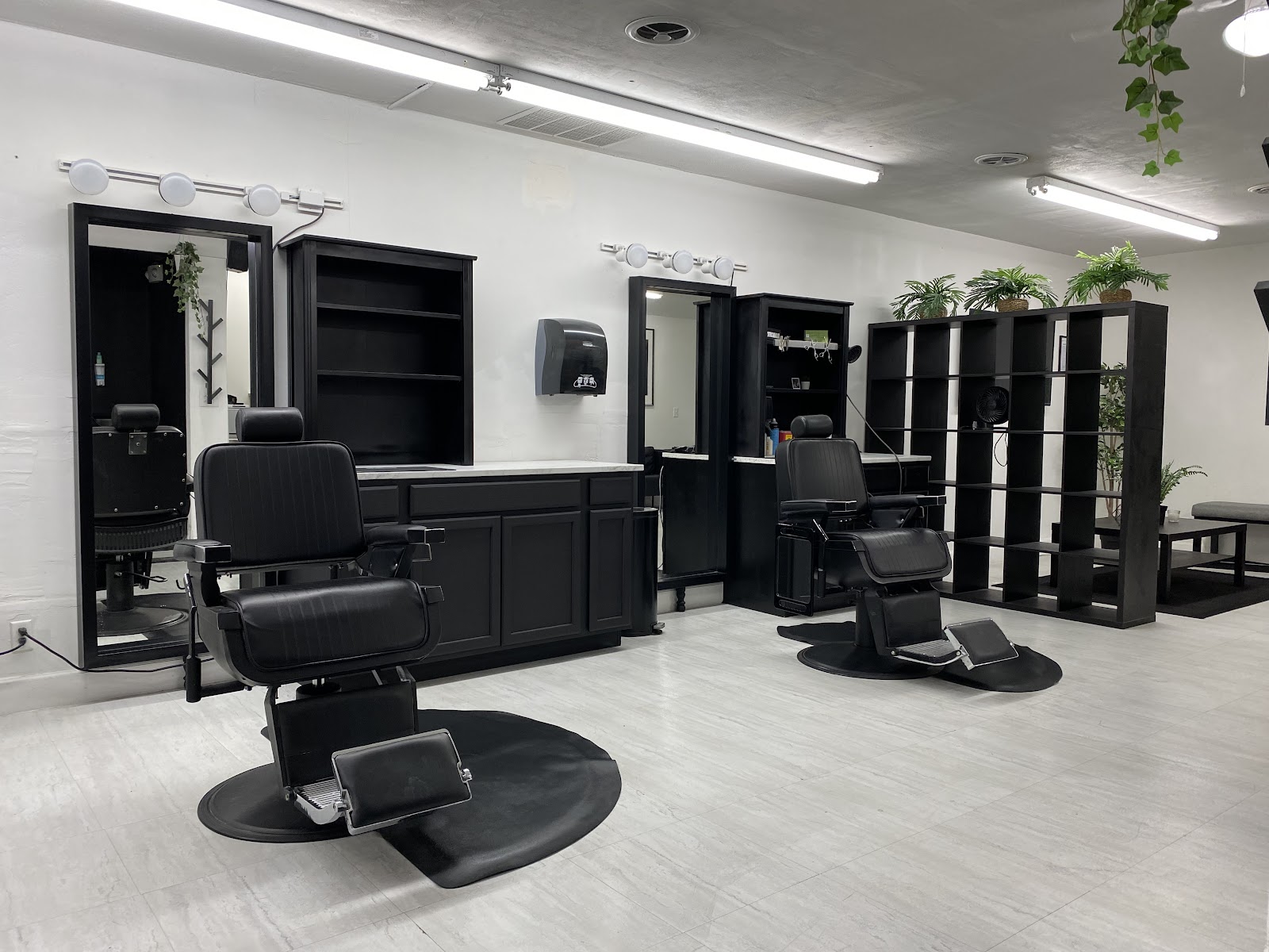 Clean modern barbershop interior with black chairs, mirrors and plants